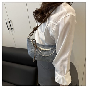 Dettaglio borsa croissant in denim con ciondoli di perle e tracolla in pelle