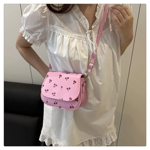 Close-up of pink PU leather crossbody bag featuring red cherry prints and flap cover