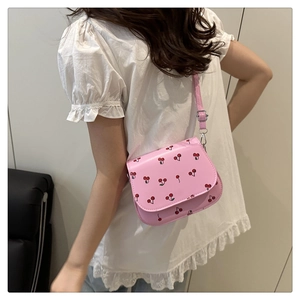 Detail view of pink crossbody bag with red cherry prints and adjustable shoulder strap
