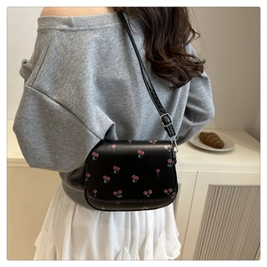 Detailed view of cherry print on black PU leather bag with adjustable strap