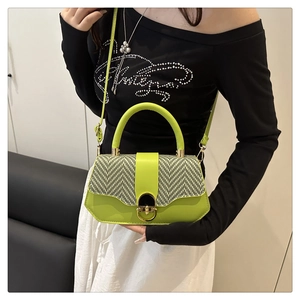 Detail of green hardshell box bag featuring houndstooth pattern and gold lock