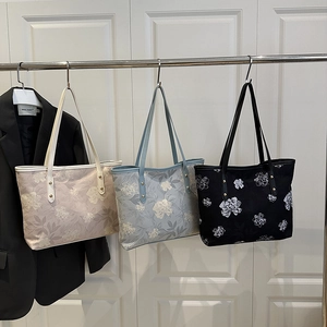 Three jacquard tote bags with floral patterns and leather handles in a showroom setting