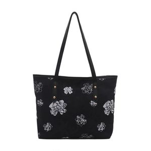 Minimalist black tote bag with white floral print and golden rivets in a front view
