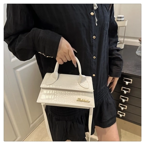 Detail of white crocodile embossed mini crossbody bag with gold metal logo and handle