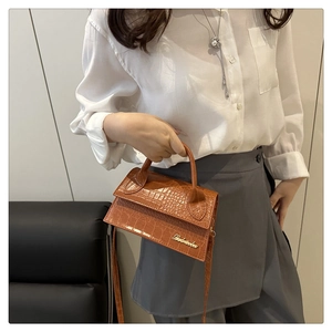 Detailed view of brown crocodile texture leather and gold metal letter on crossbody bag