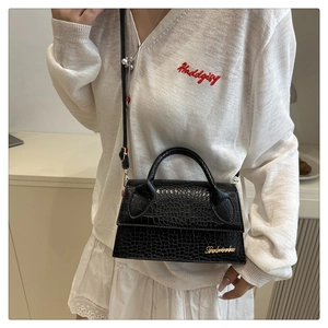 Detail of black crocodile texture leather crossbody bag with elegant gold metal logo