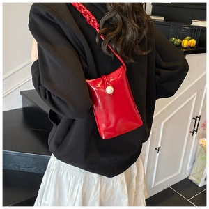 Détail du sac de téléphone en cuir verni rouge avec boucle de perle et bandoulière tressée