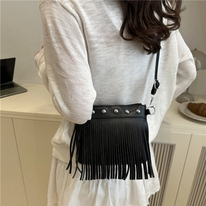 Chic black tassel bucket bag with silver studs and slim crossbody strap on model