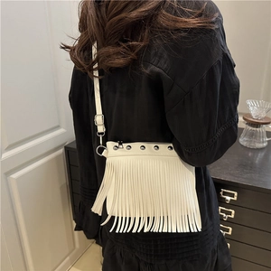 White fringe crossbody bucket bag with silver studs and adjustable strap on a model
