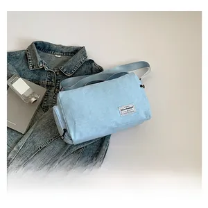 Detail of light blue canvas cylinder bag with vintage cloth label and fabric strap