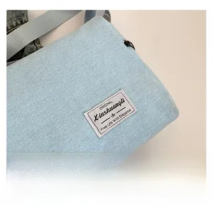 Close-up of light blue denim fabric texture and stitched label on minimalist bag