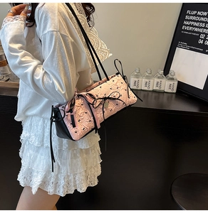 Dettaglio borsa rosa a fiori con cinturini in pelle nera e piccoli fiocchi neri
