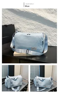 Detail view of a blue canvas crossbody bag showing metal zippers and adjustable strap