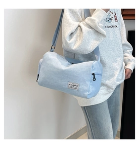 Detail of light blue cylindrical canvas bag with zip closure and woven shoulder strap