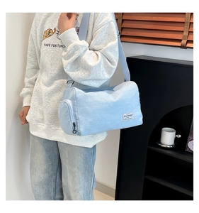 Light blue canvas boston shoulder bag with adjustable strap shown in casual setting