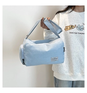 Detail of light blue waterproof nylon travel duffel bag with woven logo and wide strap