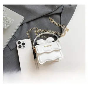 Détails du mini sac blanc avec nœud décoratif et bandoulière chaîne dorée en scène