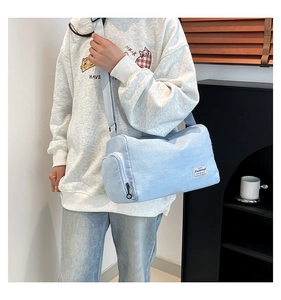Detail view of light blue canvas cylinder bag with side pocket and adjustable strap
