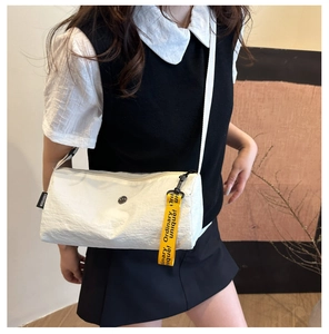 Vue détaillée du sac cylindrique blanc avec pendentif jaune et texture en toile souple