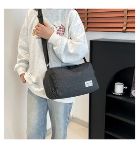 Detail of dark grey cylinder canvas crossbody bag with side zipper and woven label