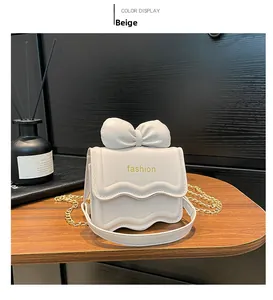 Vue détaillée du sac à bandoulière en cuir beige avec nœud et bandoulière chaîne dorée