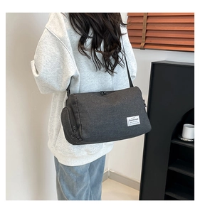 Detail of grey canvas crossbody bag showing a side view and the white fabric brand label