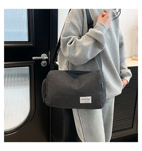 Detail view of charcoal canvas crossbody bag with adjustable strap and multi-pocket design