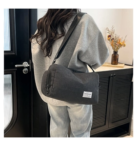 Detailed close-up of dark grey cylinder canvas crossbody bag with adjustable nylon strap