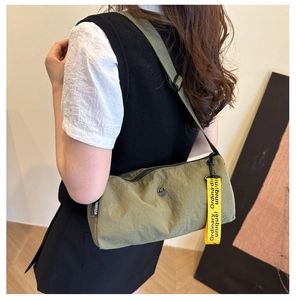 Détail du sac bandoulière cylindrique en nylon vert armée avec sangle jaune décorative