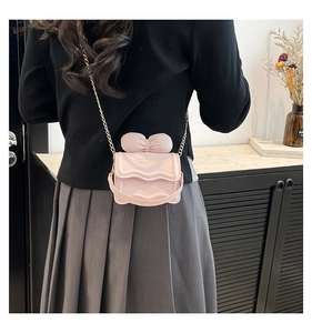 Gros plan d'un mini sac bandoulière rose avec nœud et chaîne porté par un mannequin