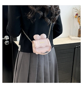 Détail d'un mini sac bandoulière rose avec chaîne dorée et nœud décoratif