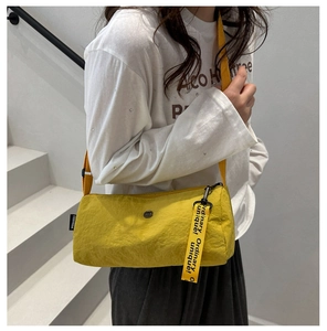 Gros plan du sac Boston en nylon jaune vif avec sangle décorative et étiquette de marque