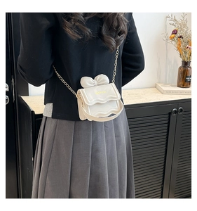 Détail du mini sac blanc avec nœud 3D, bandoulière chaîne dorée et texte fashion