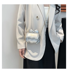 Vue détaillée du mini sac bandoulière argenté avec bord ondulé et nœud élégant