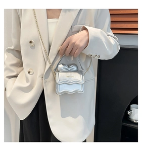 Mini sac argenté avec nœud en métal et bandoulière chaîne sur un blazer blanc