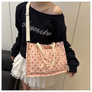 Detail of pink corduroy tote bag with red heart pattern and dual canvas straps
