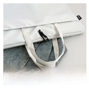 Detail of white nylon laptop bag showing sturdy handles and black FASHION woven label