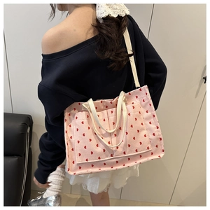 Detail of pink corduroy tote bag with red heart patterns and multiple outer pockets