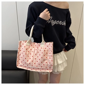 Close-up of pink corduroy tote bag with red heart embroidery and front pockets