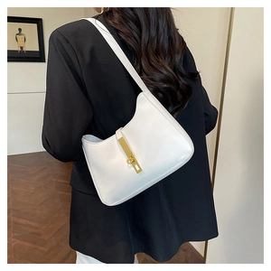 Sac sous le bras blanc en demi-lune avec fermoir doré porté sur un blazer noir