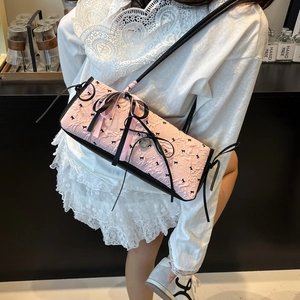 Borsa a secchiello rosa con fiocchi e dettagli in pelle nera indossata da modella