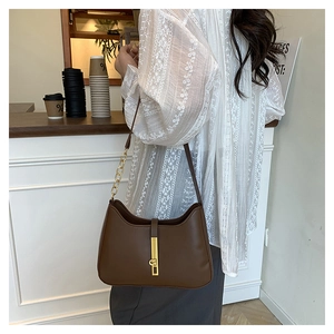 Détail du sac bandoulière en cuir marron foncé avec fermoir doré et bandoulière chaîne