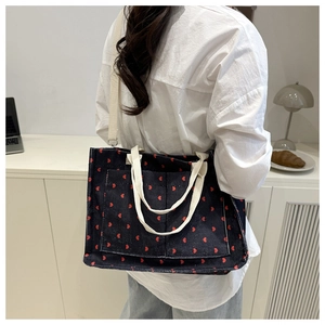 Detail of blue corduroy tote bag with red hearts and adjustable crossbody strap