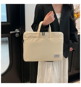 Detail of hand-held beige laptop bag with durable handles and waterproof nylon texture