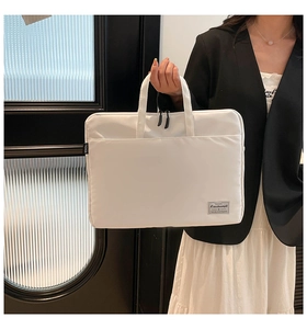 Detail of white canvas laptop bag featuring a fashion strap and durable metal zippers