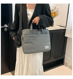 Detailed view of gray fabric laptop bag with top handle and adjustable shoulder strap