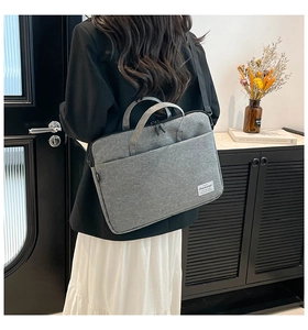 Gray canvas laptop bag with dual handles and shoulder strap shown in a daily use scene