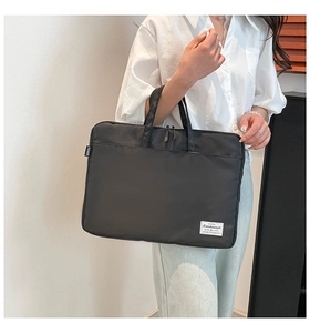 Close-up of black nylon laptop bag with reinforced handles and brand labels on the front