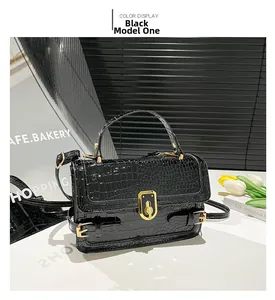 Detail of black crocodile texture bag with gold metal buckle and detachable strap