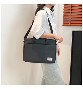 Model wearing a black nylon messenger bag with adjustable strap and shoulder carry style